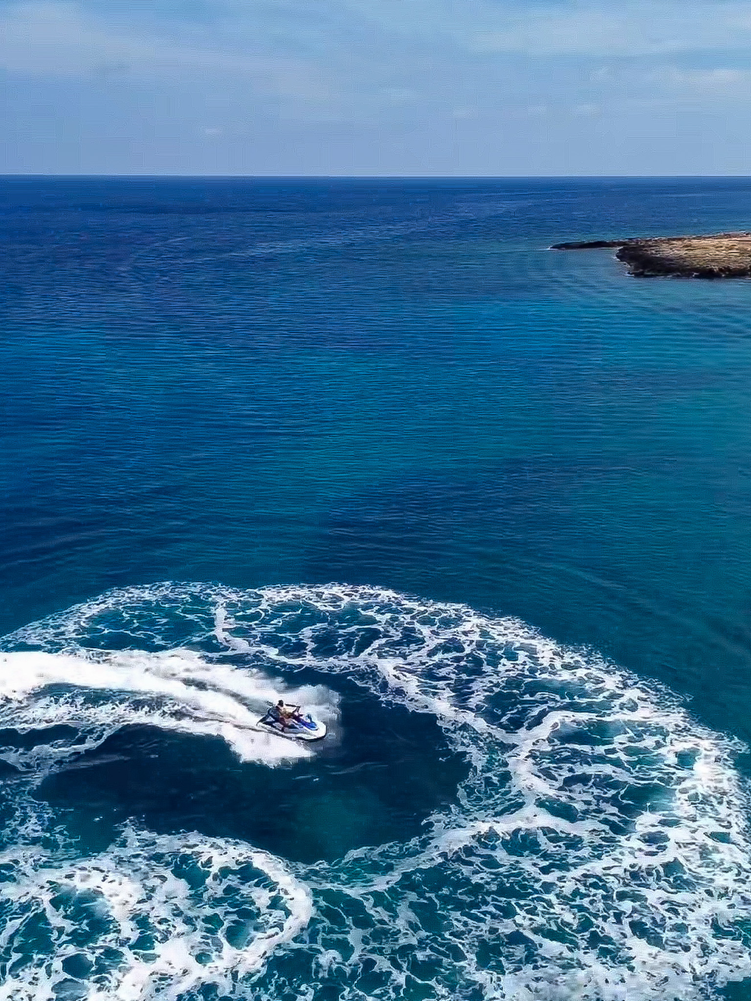 Aerial view of a jet ski making circular waves in the deep blue waters of Ayia Napa.