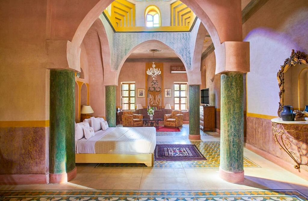 A beautifully designed suite at Al Moudira Hotel in Luxor, featuring high ceilings, Moorish-style arches, intricate tile flooring, and elegant furnishings.