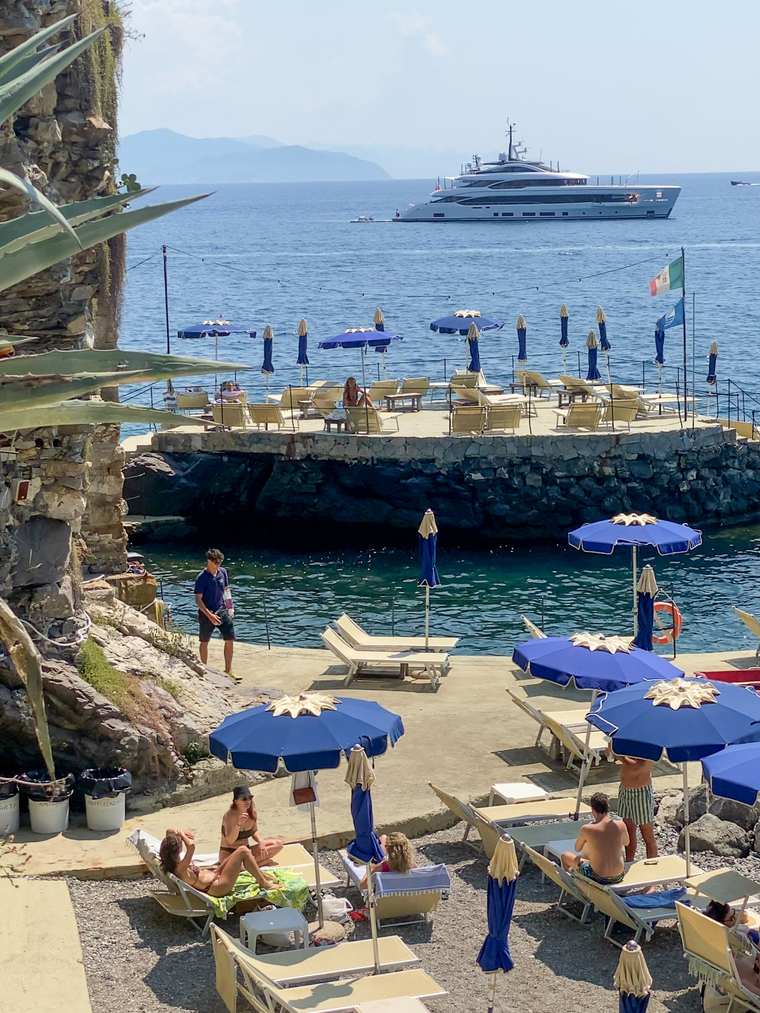 A cliffside beach club with sunbeds and a vibrant atmosphere at Covo di Nord Est in Santa Margherita Ligure.