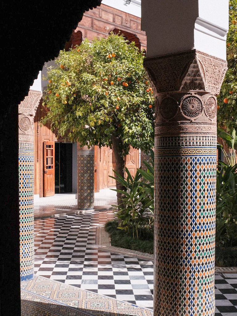 Courtyard of Dar El Bacha Museum in Marrakech, featuring intricate tilework and lush orange trees.