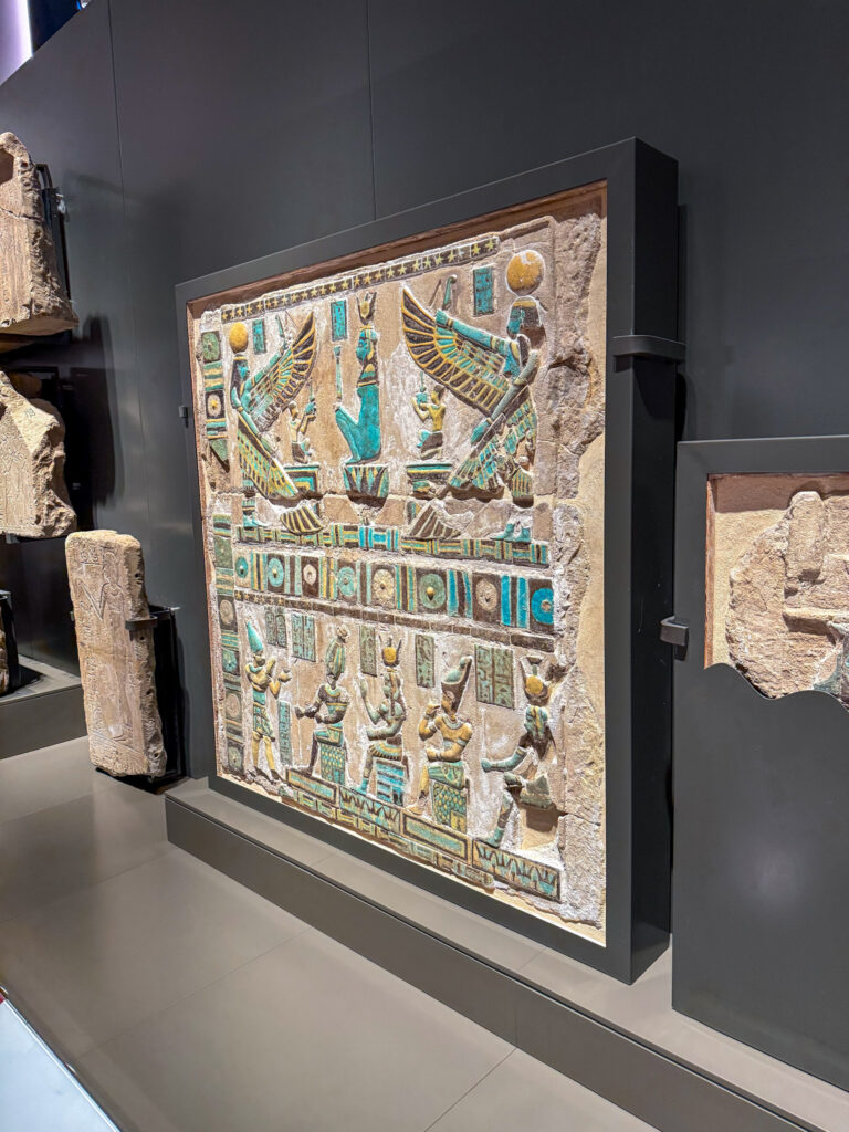 Ancient Egyptian relief at the Grand Egyptian Museum in Giza, showcasing intricate carvings and vibrant turquoise details.