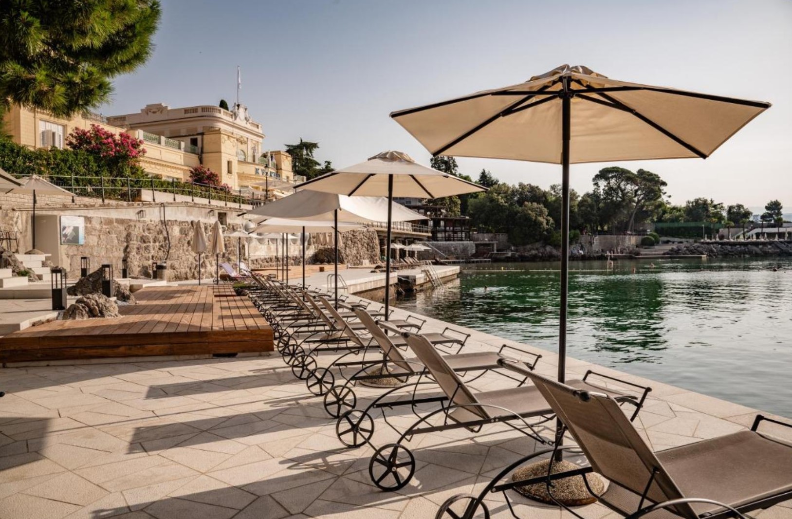 Sun loungers and umbrellas by the sea at Hotel Kvarner - Liburnia, Opatija, Croatia. A peaceful waterfront setting perfect for relaxation.