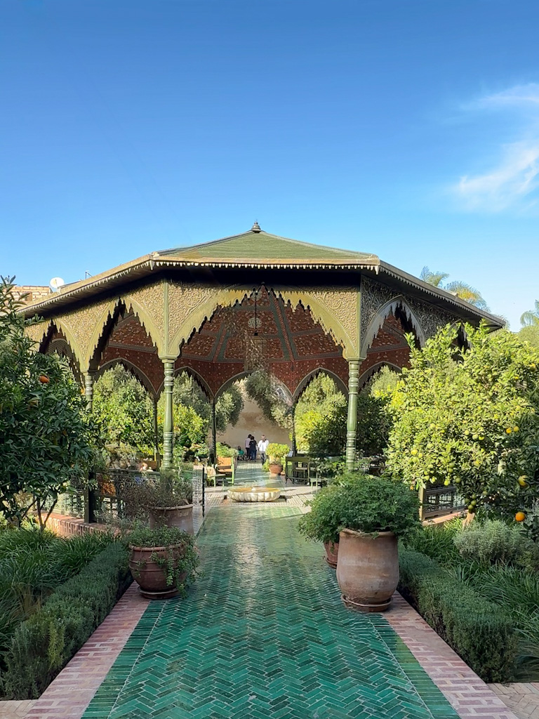 Tranquil courtyard of Le Jardin Secret in Marrakech, featuring a beautiful fountain and lush greenery.