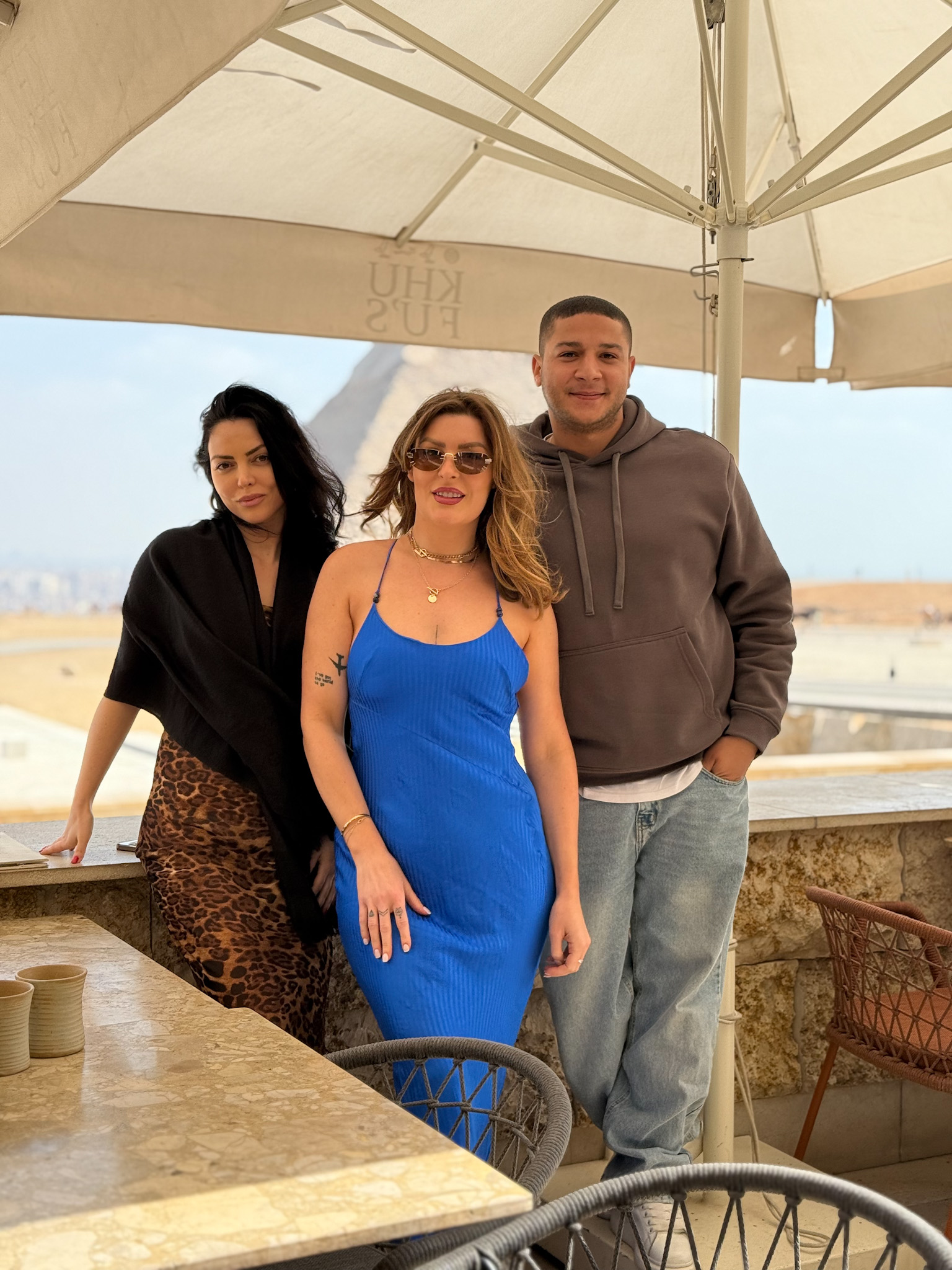 A group of three people posing at Kufu’s restaurant near the Giza Pyramids, enjoying a scenic lunch with a view.