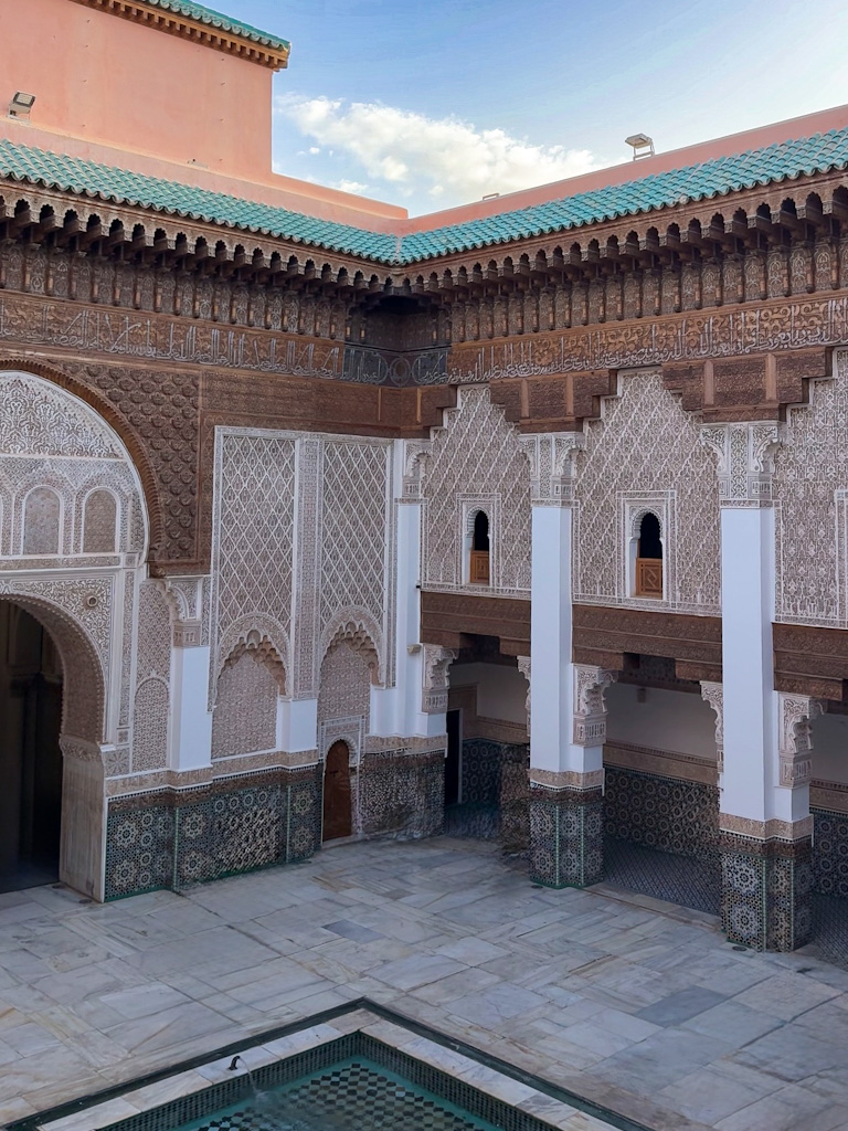 The stunning courtyard of Medersa Ben Youssef in Marrakech, showcasing intricate Moroccan tilework and traditional Islamic architecture