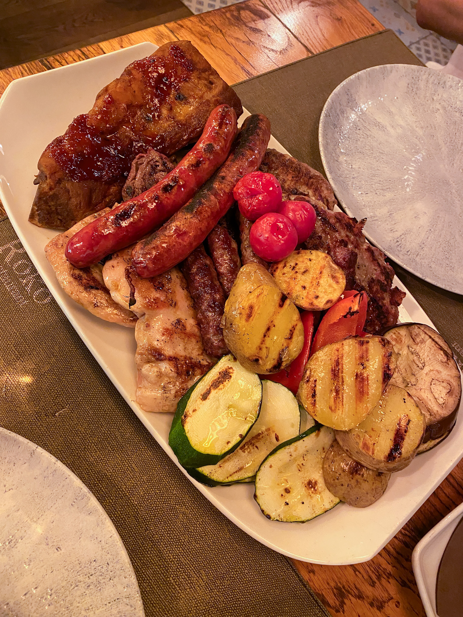 Croatian mixed grill platter at Restaurant Roko in Opatija, loaded with juicy sausages, tender ribs, grilled chicken, and roasted vegetables.