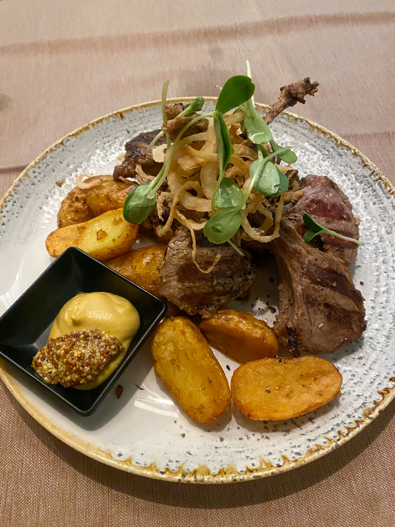 Grilled lamb chops served with crispy roasted potatoes, fried onions, and mustard sauce at Restaurant Ruzmarin in Opatija, Croatia