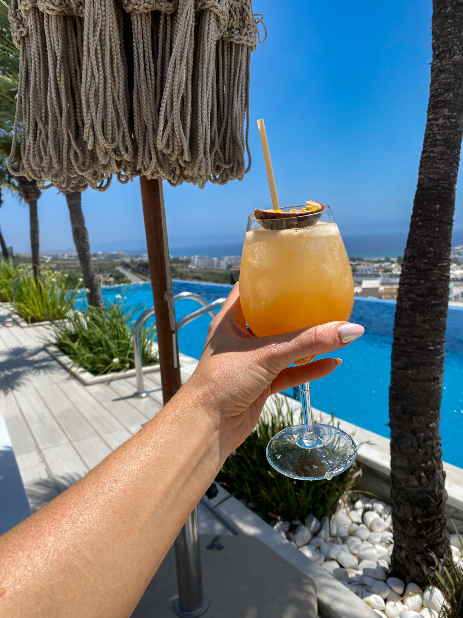 A refreshing passion fruit cocktail held by the poolside at Napa View Sky Lounge, overlooking the stunning coastline of Ayia Napa.