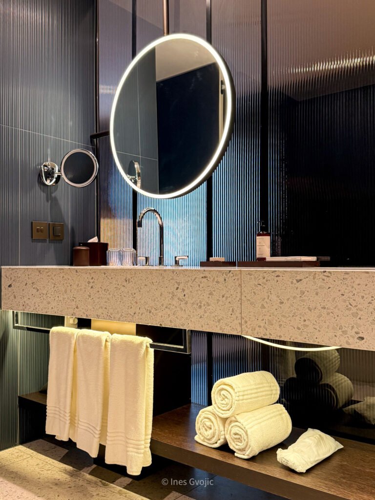 Elegant bathroom vanity with towels and round mirror at Dorothea Hotel Budapest