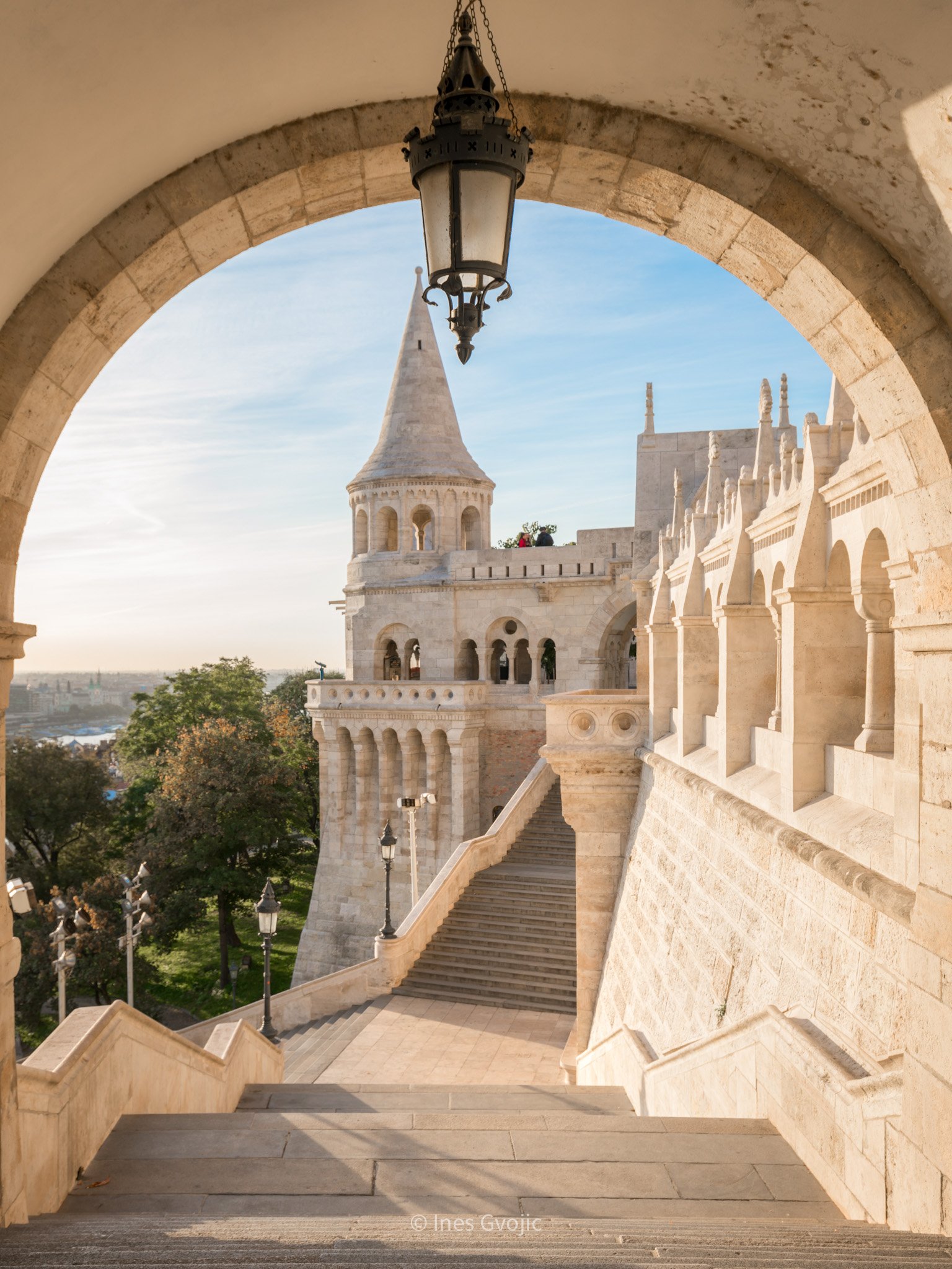 Stone archway framing Fisherman’s Bastion with soft morning light in Budapest