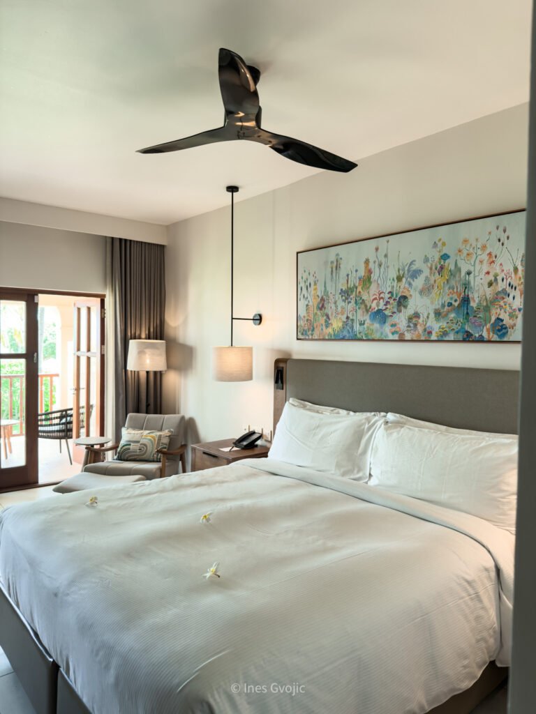 Bright garden view room with king bed and balcony at Hilton Mauritius Resort & Spa.