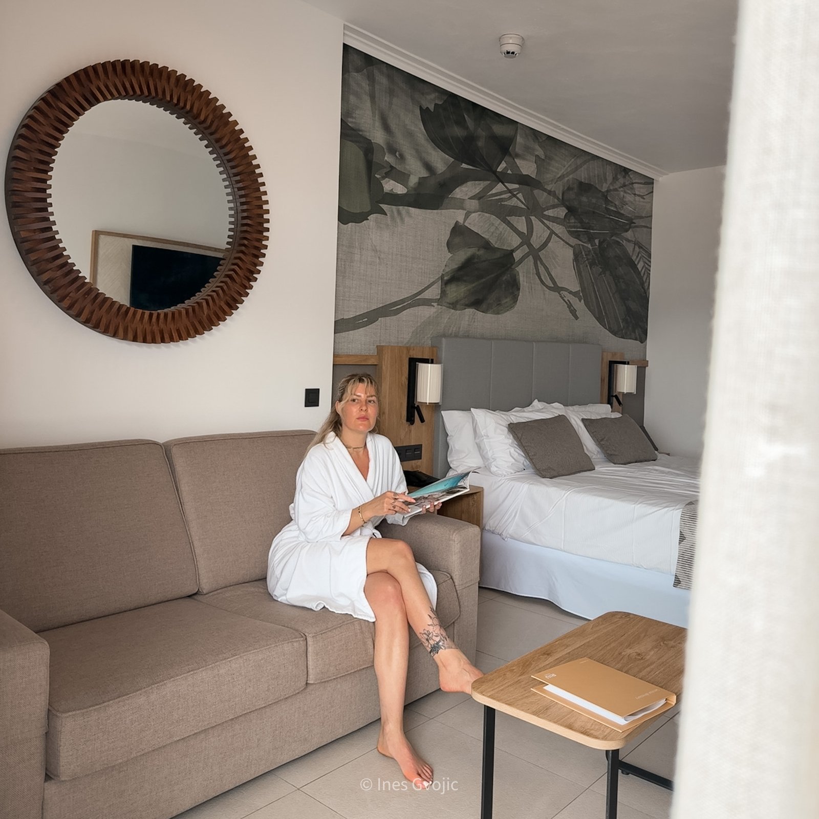 Woman sitting on sofa in modern suite with neutral decor at Riu Palace Hotel Mauritius.
