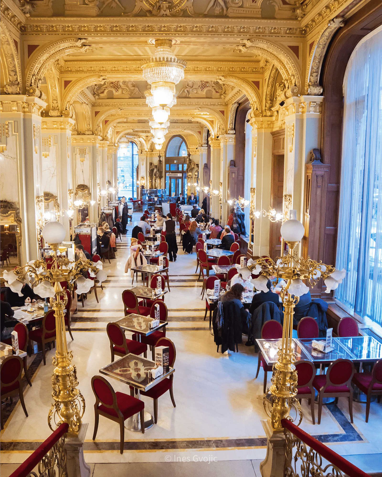 Lavishly decorated interior of New York Café in Budapest with chandeliers and red velvet chairs
