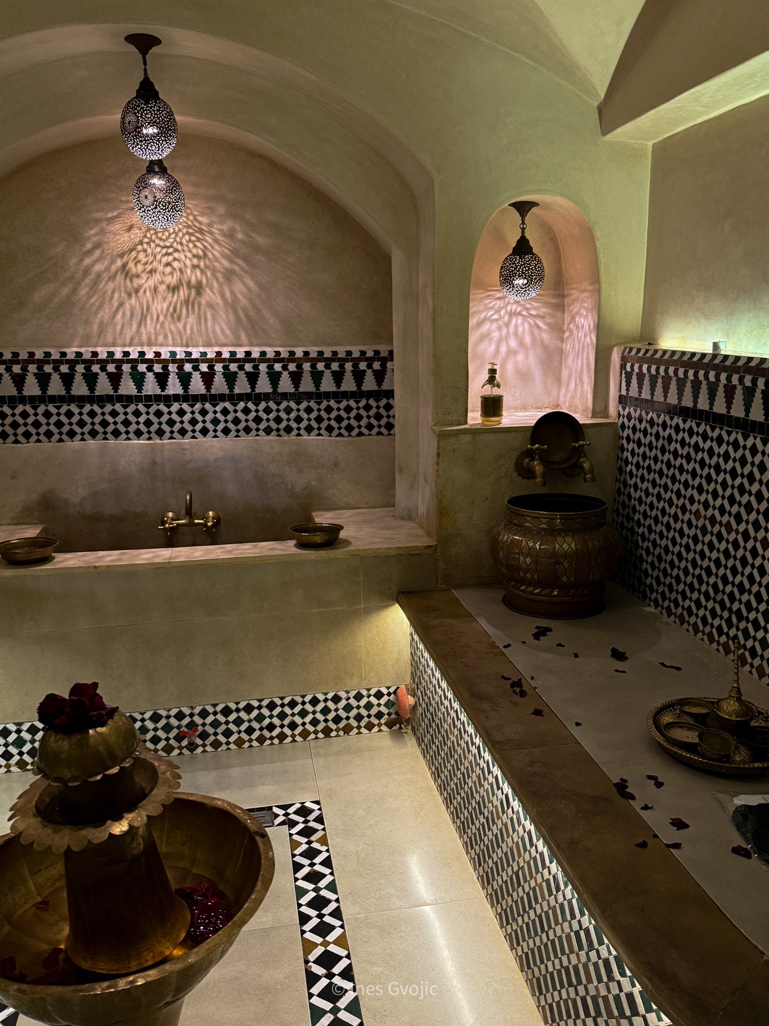 Interior of a Moroccan hammam at Marajah Spa in Marrakech with mosaic tiles, brass fixtures, and soft ambient lighting.