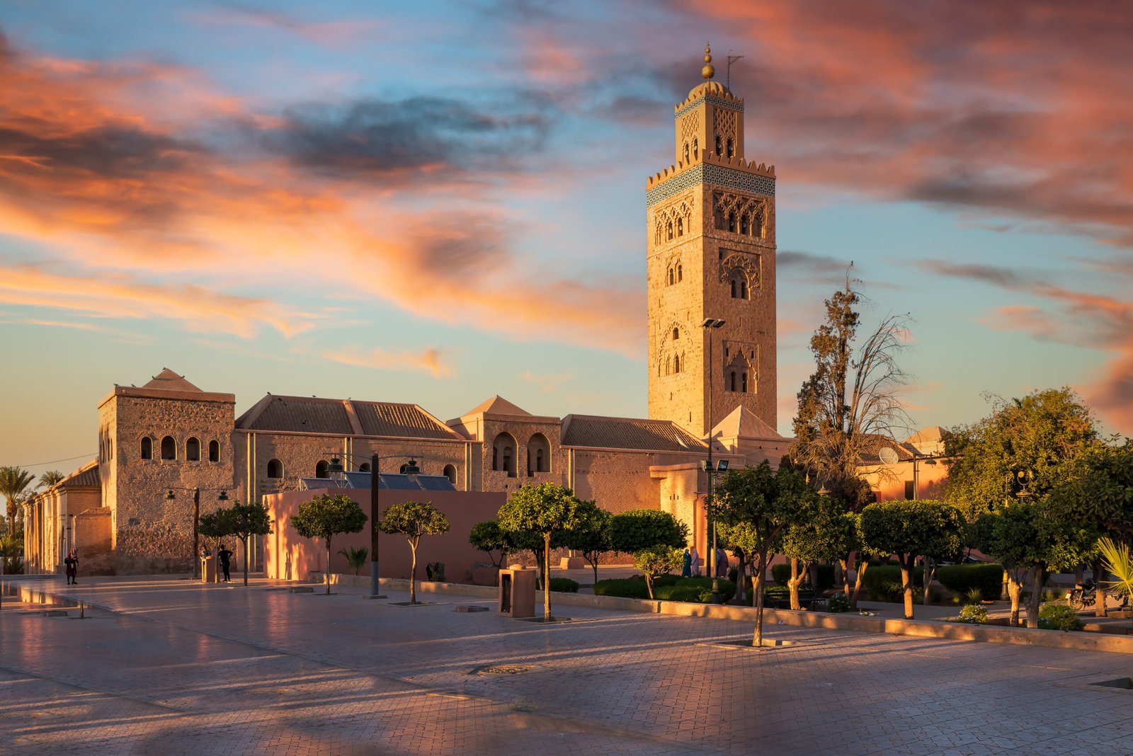 Koutoubia Mosque in Marrakech illuminated by sunset light with pink and orange clouds in the sky.
