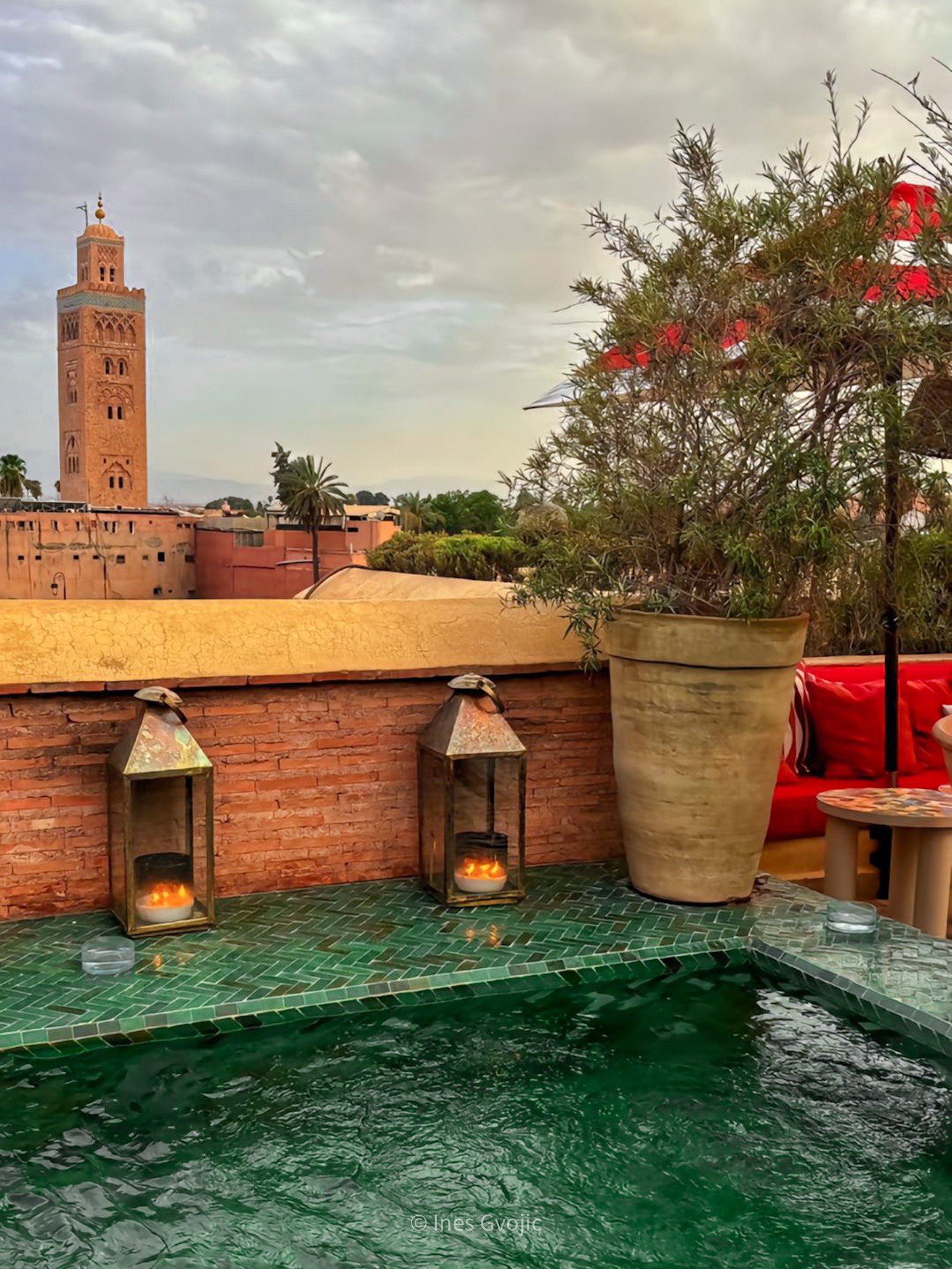 Green tiled rooftop pool at El Fenn with lanterns and a view of the Koutoubia Mosque in Marrakech.