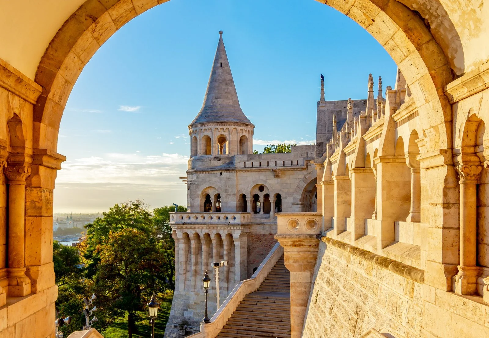 Fisherman’s Bastion in Budapest at sunrise, viewed through a stone arch