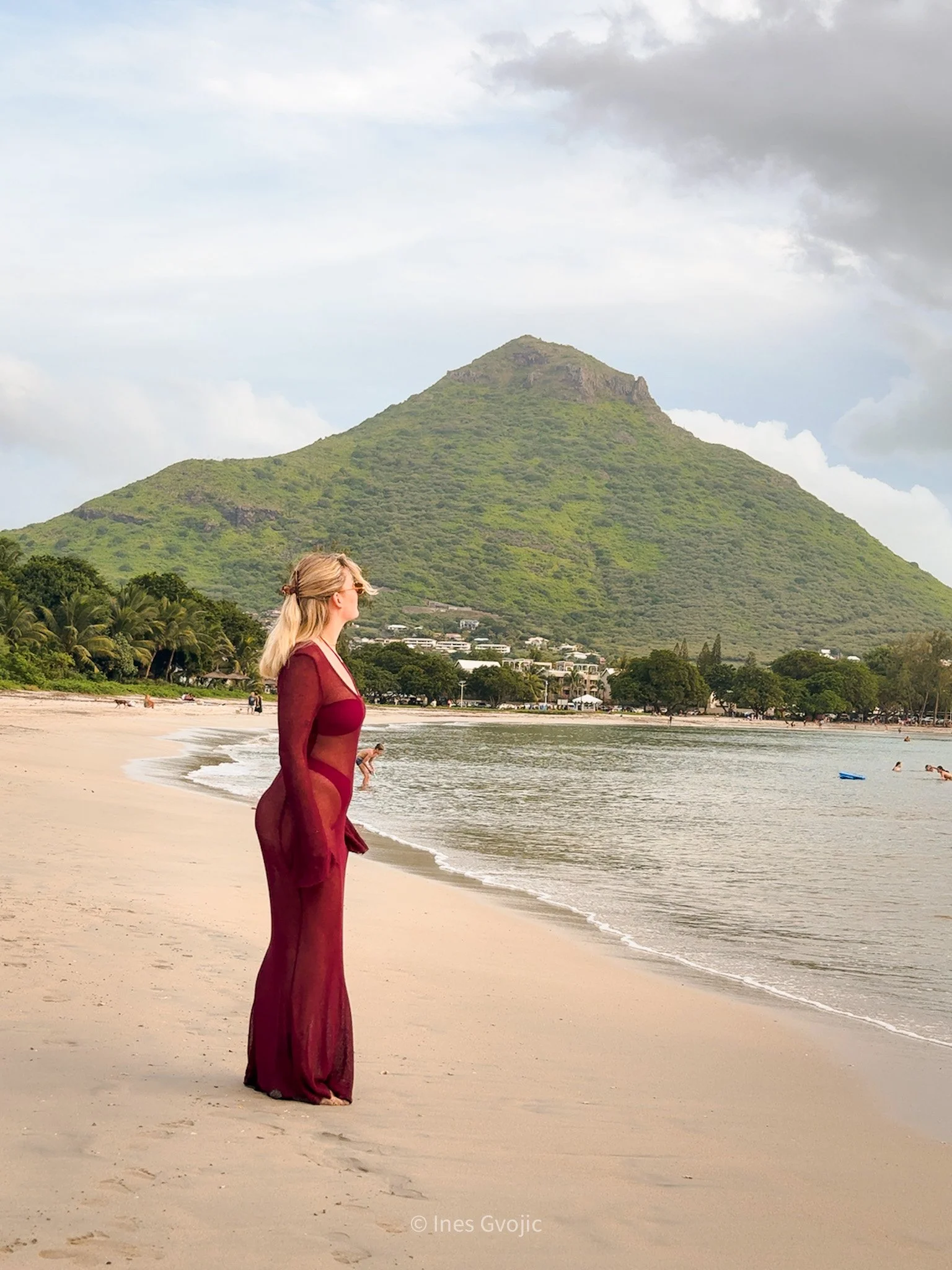 Woman standing on Tamarin Bay Beach with La Tourelle Mountain in the background, Mauritius.