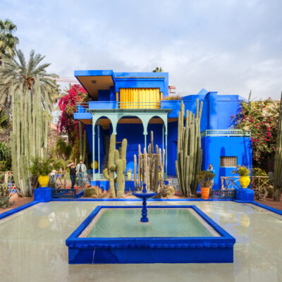 Le Jardin Majorelle in Marrakech, Morocco – vibrant blue villa surrounded by lush gardens and towering cactus plants